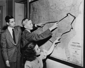 AFS Participants Jean Paly (France), Kees de Kujper (Netherlands), and Sarka Sramkova (Czechoslovakia) look over their American bus trip route. 1948.