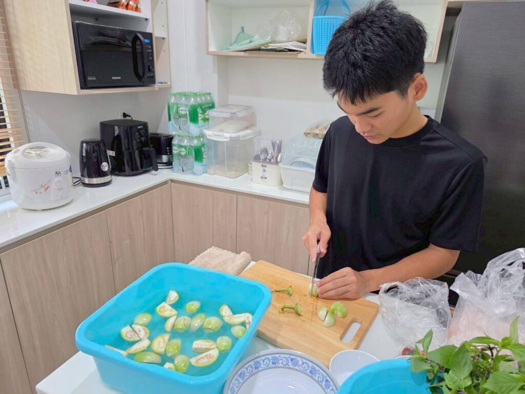Japanese exchange student Haruma chopping Thai eggplants to cook a traditional Thai curry