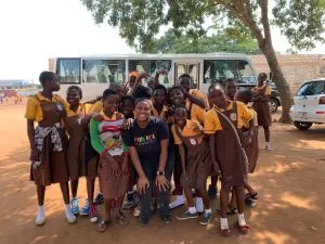 Antoinette with school children in front of bus in Ghana
