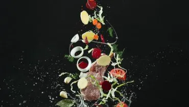 Fresh vegetables falling into a stainless steel casserole