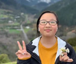 Student giving peace sign in front of mountains