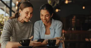 Two friends looking at a phone drinking coffee