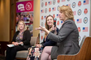 Educator giving presentation on stage with a panel.