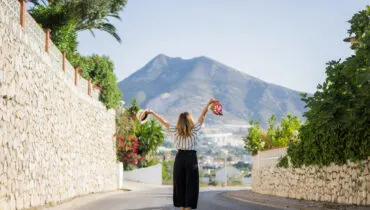 young beautiful woman on vacation jumping. In one hand sandals i