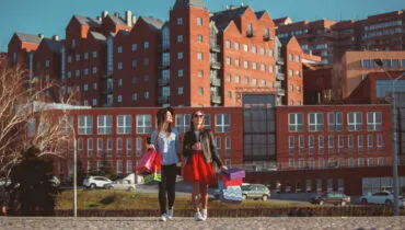 Two girls walking with shopping on city streets