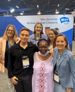 Representatives from AFS Intercultural Programs, partner organizations, and NAFSA CEO Dr. Fanta Aw pose together at the AFS exhibit booth during NAFSA 2026.