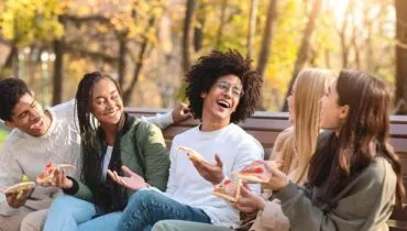 young-international-friends-eating-pizza-together-in-public-park-having-good-time-outdoors-photo