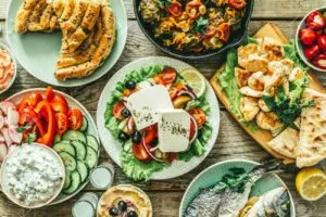 Selection of traditional greek food – salad, meze, pie, fish, tzatziki, dolma on wood background