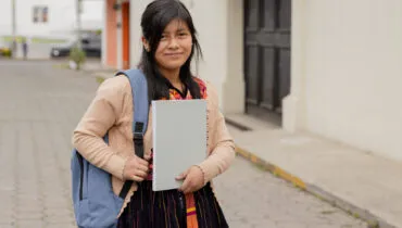 Hispanic young woman with notebook and backpack outside school in rural area – Mayan woman ready to go to study – Latina student in the city