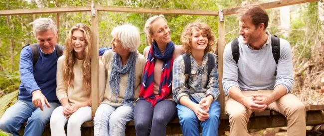 Family group sitting on a bridge in a forest, full length