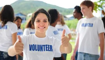 happy volunteer girl showing thumbs up sign