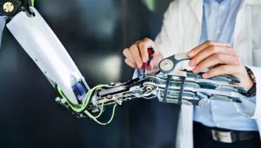 Unrecognizable scientist with a robot, mending or inventing.